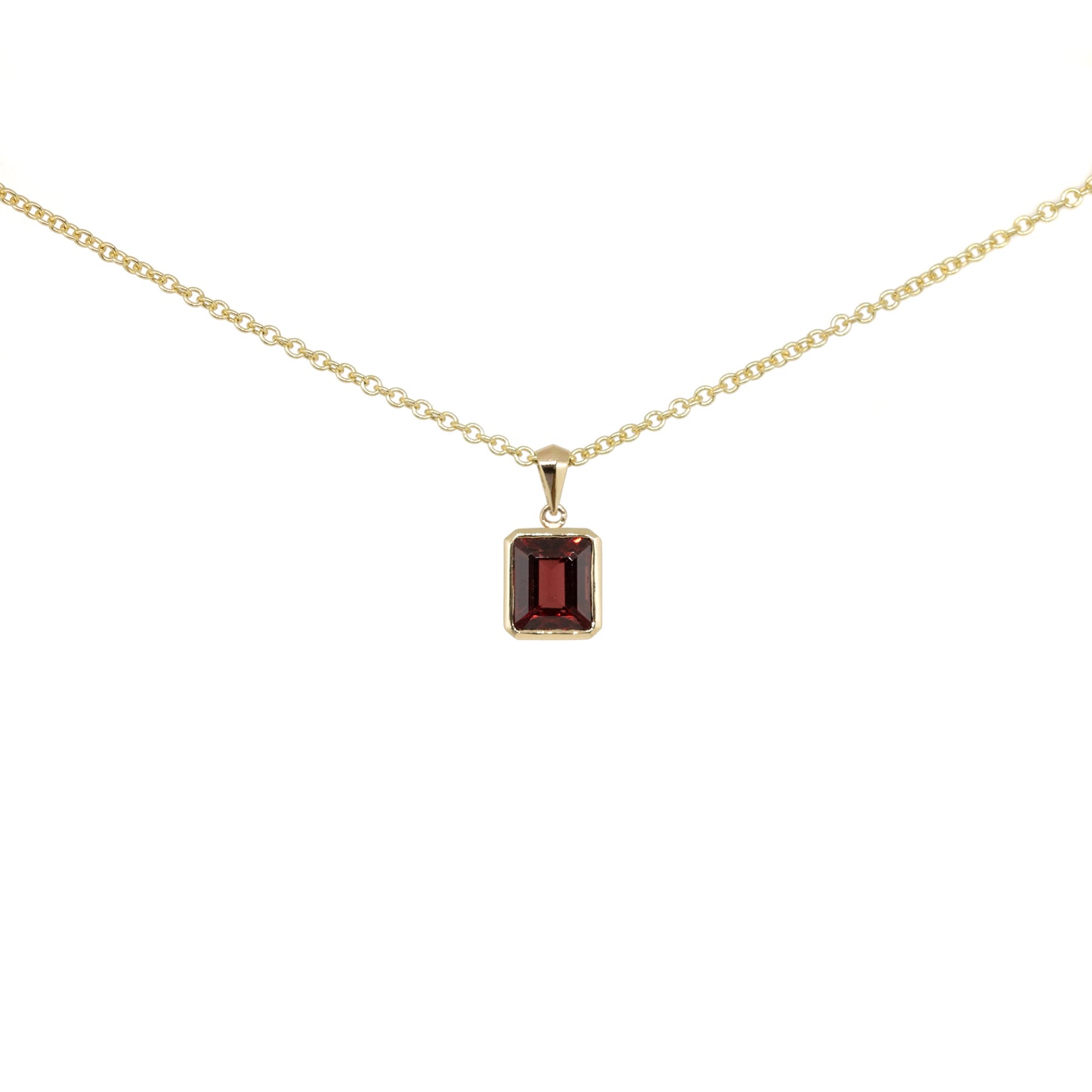 Gold necklace with a garnet step cut pendant on a white background