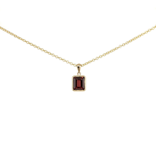 Gold necklace with a garnet step cut pendant on a white background