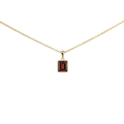 Gold necklace with a garnet step cut pendant on a white background