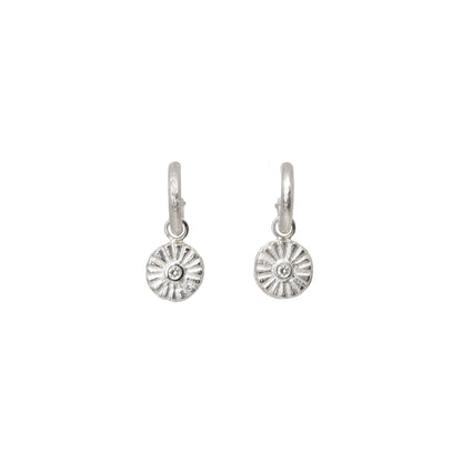 Pair of silver hoop earrings with circular diamond charms designs on a white background