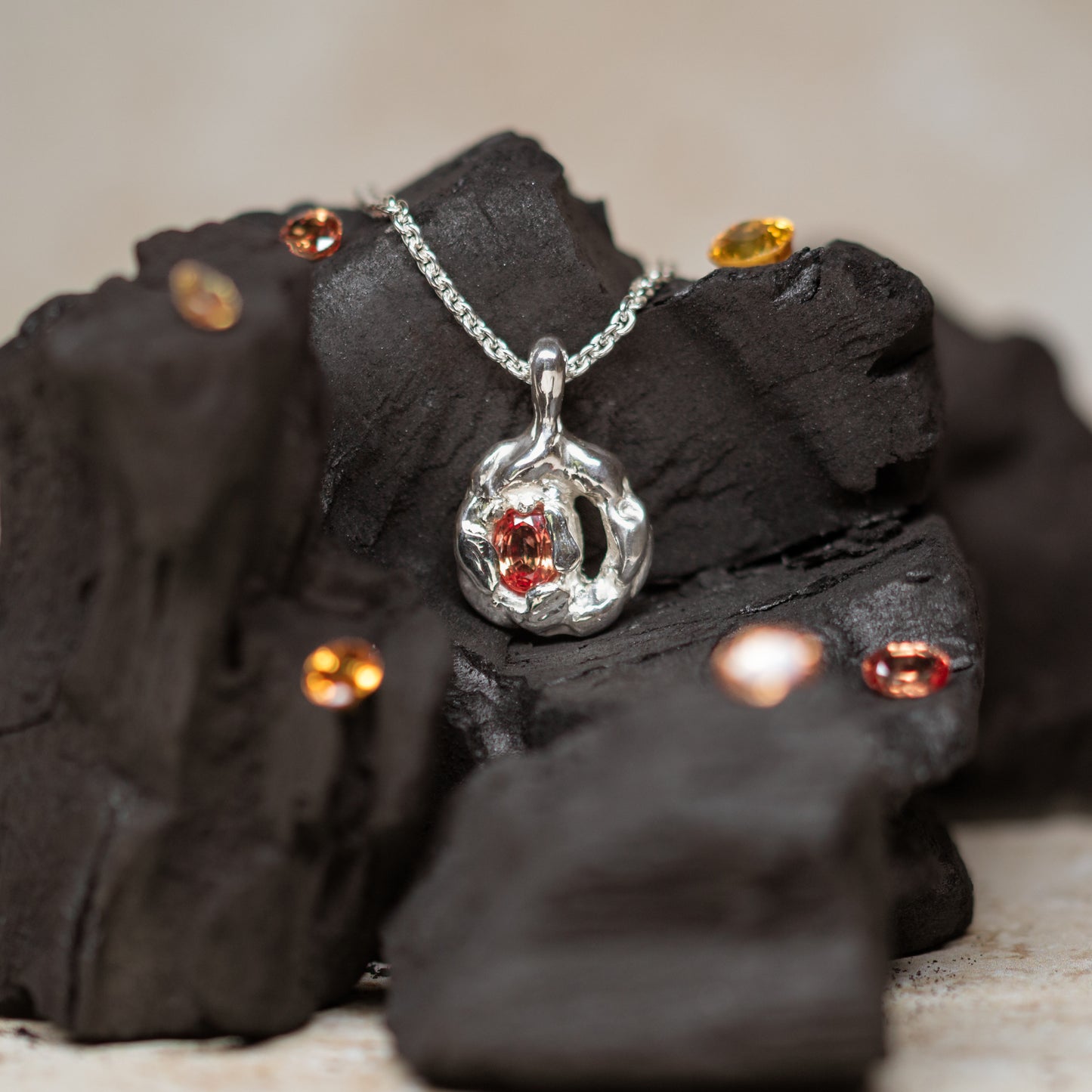 Silver pendant with orange sapphire on charcoal