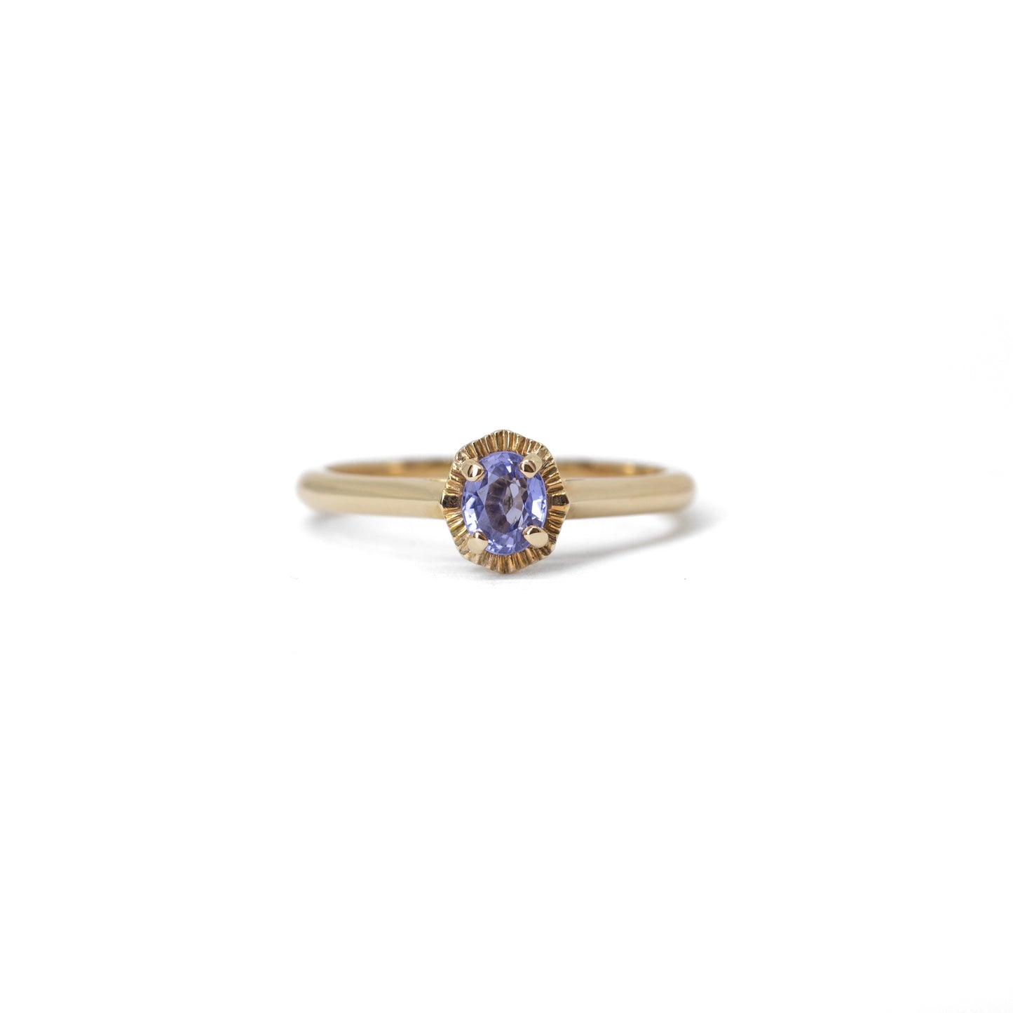 Gold ring with a blue sapphire gemstone on a white background