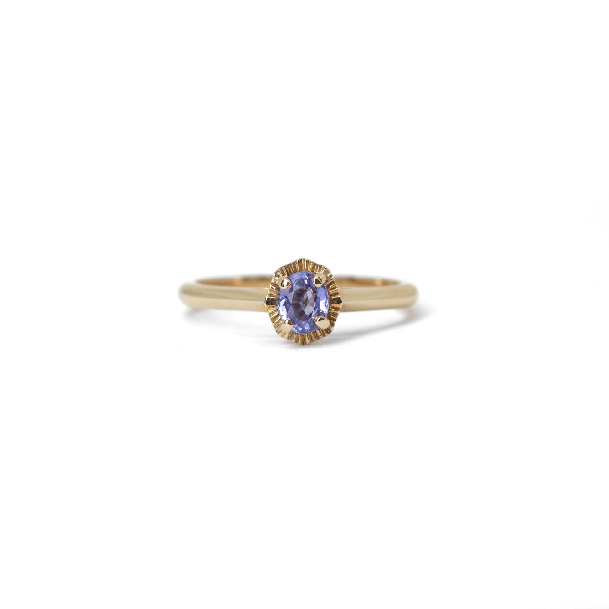 Gold ring with a blue sapphire gemstone on a white background